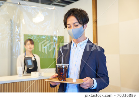 一個年輕人在一家咖啡館買冰咖啡 70336889