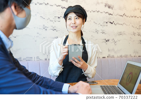 戴著透明口罩，在一家咖啡館點菜的女人 70337222