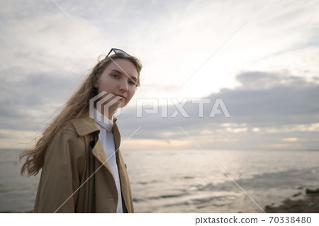pretty girl walking on a beach in beige trench coat with warm evening light pretty girl walking on a beach in beige trench coat with warm evening light 70338480