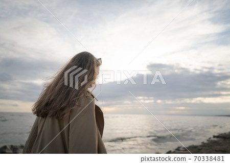 pretty girl walking on a beach in beige trench coat with warm evening light pretty girl walking on a beach in beige trench coat with warm evening light 70338481