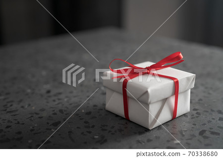 Gift white box with red bow on a gray concrete countertop Gift white box with red bow on a gray concrete countertop 70338680