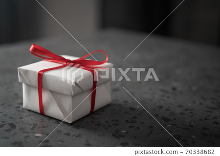 Gift white box with red bow on a gray concrete countertop Gift white box with red bow on a gray concrete countertop 70338682