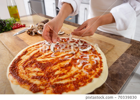 Close-up on the hands of a cook laying mushrooms on a pizza. Vegan food. 70339830