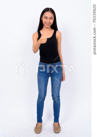 Full body shot of happy young beautiful Asian woman giving thumbs up Full body shot of happy young beautiful Asian woman giving thumbs up 70339920