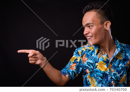 Portrait of happy young Indian tourist man pointing to the side Portrait of happy young Indian tourist man pointing to the side 70340700