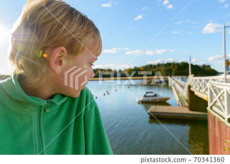 Profile view of young handsome boy looking at view of wooden pier near the river 70341360