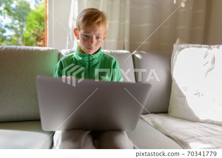 Young handsome boy using laptop on the couch at home Young handsome boy using laptop on the couch at home 70341779