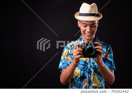 Portrait of happy young Indian tourist man taking picture with camera Portrait of happy young Indian tourist man taking picture with camera 70342442