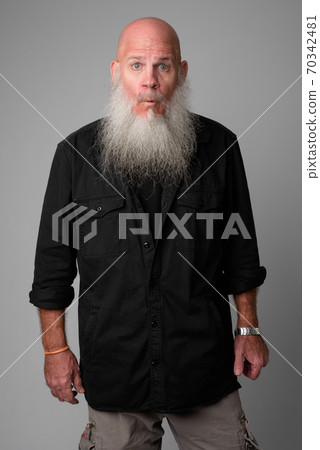 Mature handsome bald man with long beard looking shocked Mature handsome bald man with long beard looking shocked 70342481