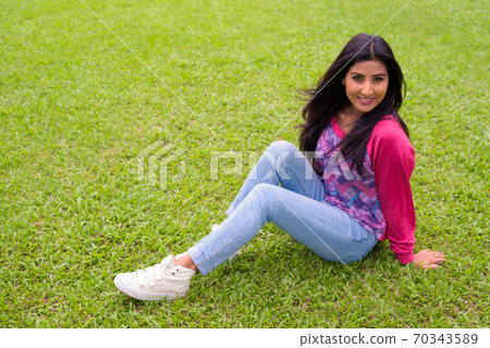 Happy young beautiful Persian woman relaxing at the park 70343589