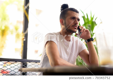 Handsome Turkish man with curly hair relaxing at the coffee shop Handsome Turkish man with curly hair relaxing at the coffee shop 70343752