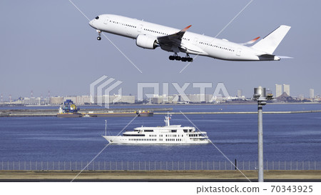 A jumbo jet taking off from Haneda Airport and a passenger ship traveling in the sea against the backdrop of the blue sky 70343925