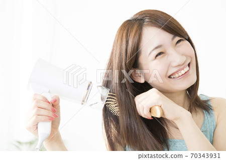 Woman doing a hair dryer Woman doing a hair dryer 70343931