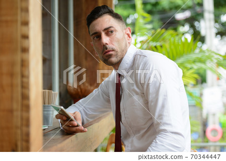 Portrait of businessman thinking while using phone at the coffee shop Portrait of businessman thinking while using phone at the coffee shop 70344447
