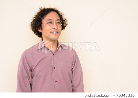 Portrait of happy Japanese businessman with curly hair thinking Portrait of happy Japanese businessman with curly hair thinking 70345336