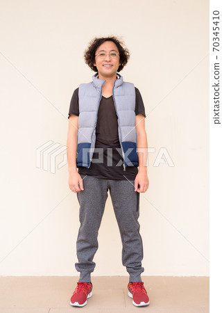 Full body shot of happy Japanese man with curly hair smiling Full body shot of happy Japanese man with curly hair smiling 70345410