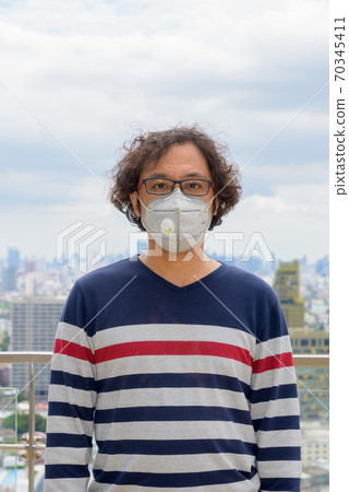 Portrait of Japanese man wearing mask against view of the city Portrait of Japanese man wearing mask against view of the city 70345411