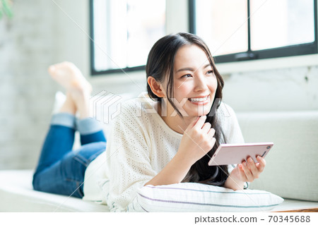 一個年輕的女人，看著她的智能手機上的視頻 70345688