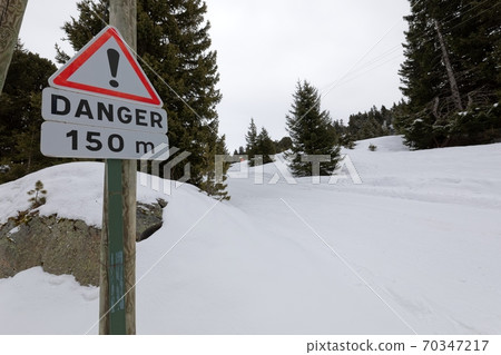 Snowy mountain road streching through the hills 70347217