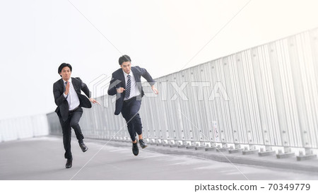 Two businessmen running at full power 70349779