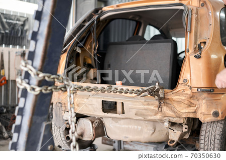 A broken car with a violation of geometry is on the stocks for leveling. Restoration of vehicles with chain and hook. Repair in the workshop and auto 70350630