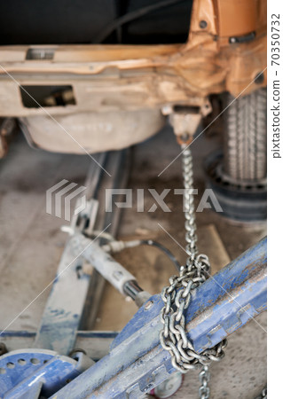 A broken car with a violation of geometry is on the stocks for leveling. Restoration of vehicles with chain and hook. Repair in the workshop and auto 70350732