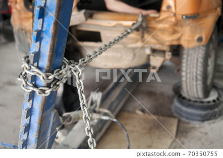 A broken car with a violation of geometry is on the stocks for leveling. Restoration of vehicles with chain and hook. Repair in the workshop and auto 70350755