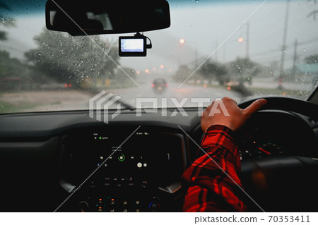 Man driving a car in the rain at night driving bad weather conditions on road 70353411
