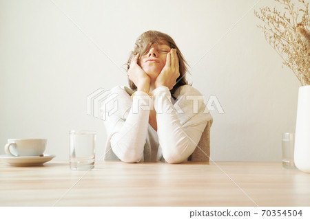 Woman is sitting ina cafe wiyh tooth ach 70354504