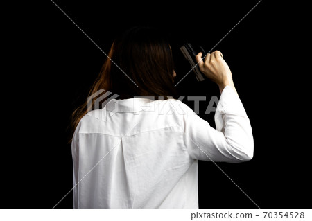 Asian woman portrait holding a gun beside the body 70354528