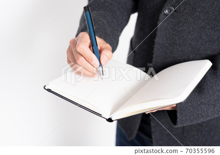 A man writing notes in a notebook 70355596