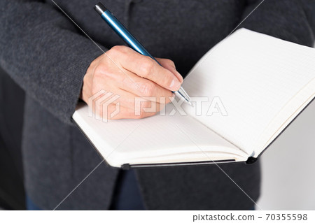 A man writing notes in a notebook 70355598