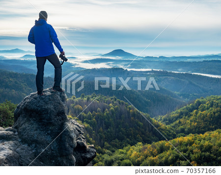 Camera in the hand of man tourist standing on rock 70357166
