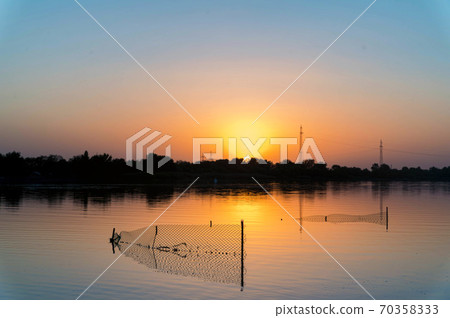 Stationary lift net fishing trap at river on sunset 70358333