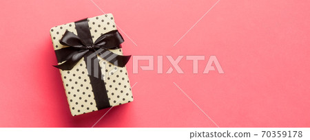 Top view Christmas present box with black bow on living coral background with copy space Top view Christmas present box with black bow on living coral background with copy space 70359178