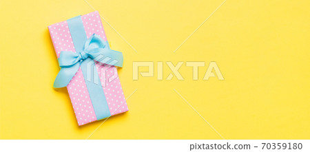 Top view Christmas present box with blue bow on yellow background with copy space Top view Christmas present box with blue bow on yellow background with copy space 70359180