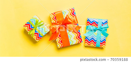 Gift box with blue, green and orange bow for Christmas or New Year day on yellow background, top view Gift box with blue, green and orange bow for Christmas or New Year day on yellow background, top view 70359188