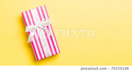 Top view Christmas present box with white bow on yellow background with copy space Top view Christmas present box with white bow on yellow background with copy space 70359196