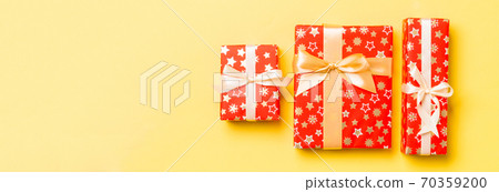 wrapped Christmas or other holiday handmade present in paper with gold ribbon on yellow background. Present box, decoration of gift on colored table, top view wrapped Christmas or other holiday handmade present in paper with gold ribbon on yellow background. Present box, decoration of gift on colored table, top view 70359200