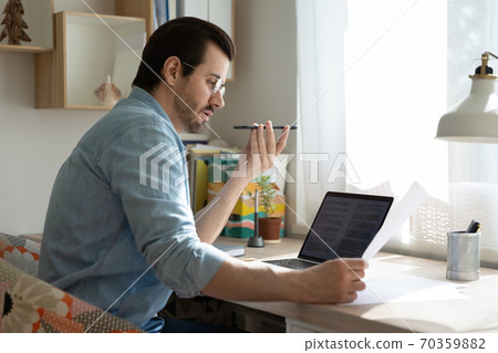 Concentrated young man dictating audio message in mobile application. 70359882