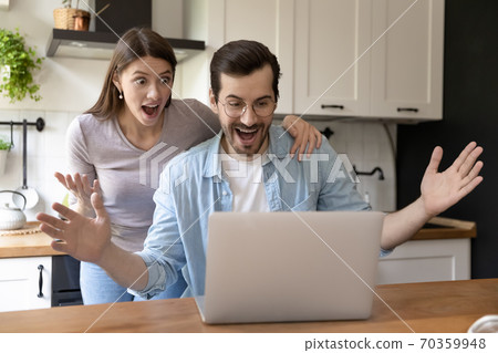 Shocked happy young family couple looking at computer screen. Shocked happy young family couple looking at computer screen. 70359948