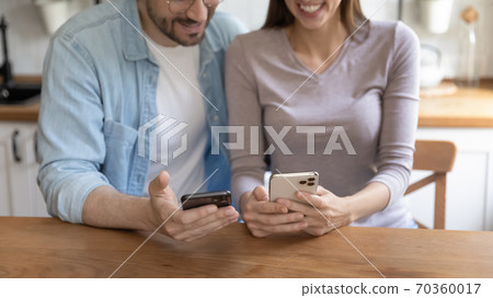 Close up addicted to technology young family couple holding smartphones. 70360017