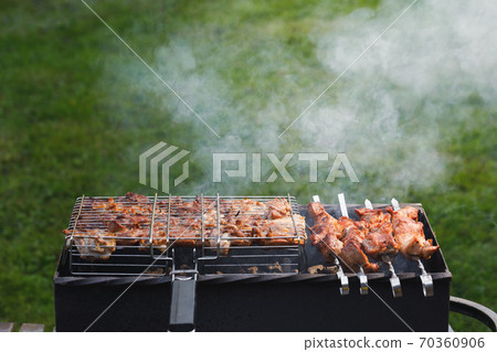 grill barbecue meat on a brazier with smoke, green grass background grill barbecue meat on a brazier with smoke, green grass background 70360906