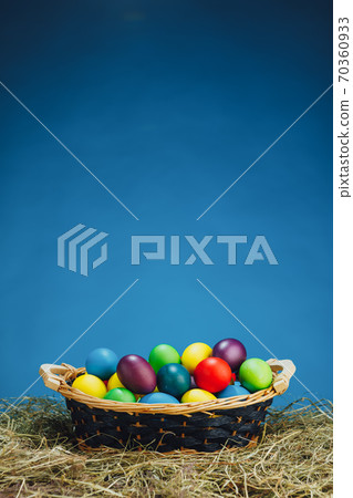 Easter basket with multicolor eggs, blue background Easter basket with multicolor eggs, blue background 70360933