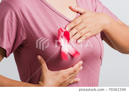woman wear pink t-shirt she have pink breast cancer awareness ribbon on chest she hold breast by hand woman wear pink t-shirt she have pink breast cancer awareness ribbon on chest she hold breast by hand 70361590