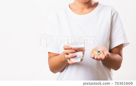 Woman hold pill drugs in hand ready take medicines with a glass of water 70361609