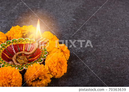clay lit Diya or oil lamp and yellow flower 70363639