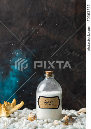 Corked, filled jar of salt and stands on white stones. Concept. Corked, filled jar of salt and stands on white stones. Concept. 70363725