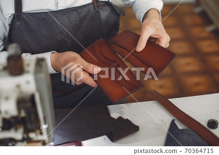 Man in a studio creates leather ware Man in a studio creates leather ware 70364715