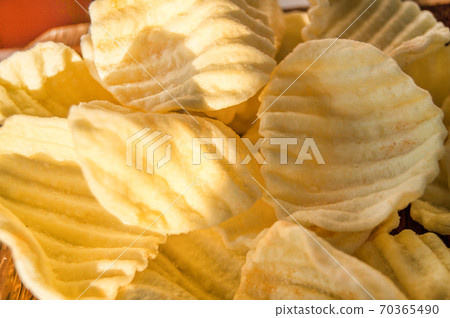 Yellow delicious salty potato chips in the background 70365490